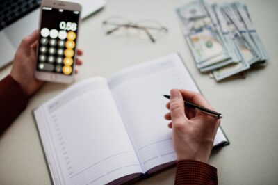 Mann Schreibt Verkäufe in Kassenbuch und rechnet mit dem Taschenrechner