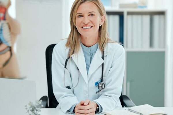 Ärztin sitzt in ihrer Praxis und lächelt