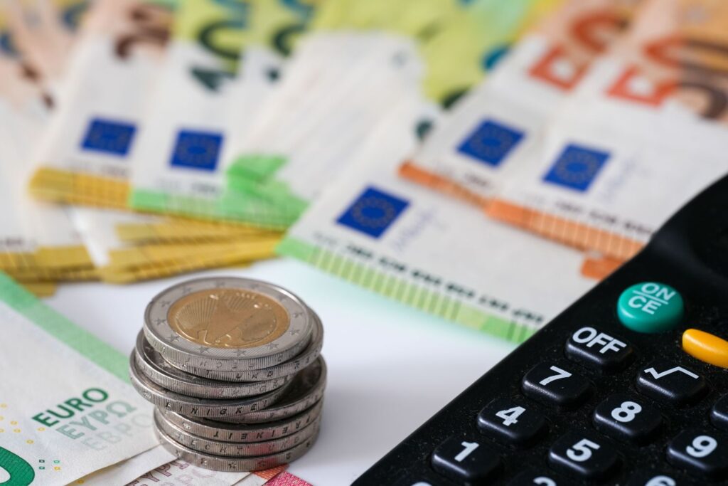 Nahaufnahme eines Stapels von 2 Euro Münzen sowie einiger Geldscheine